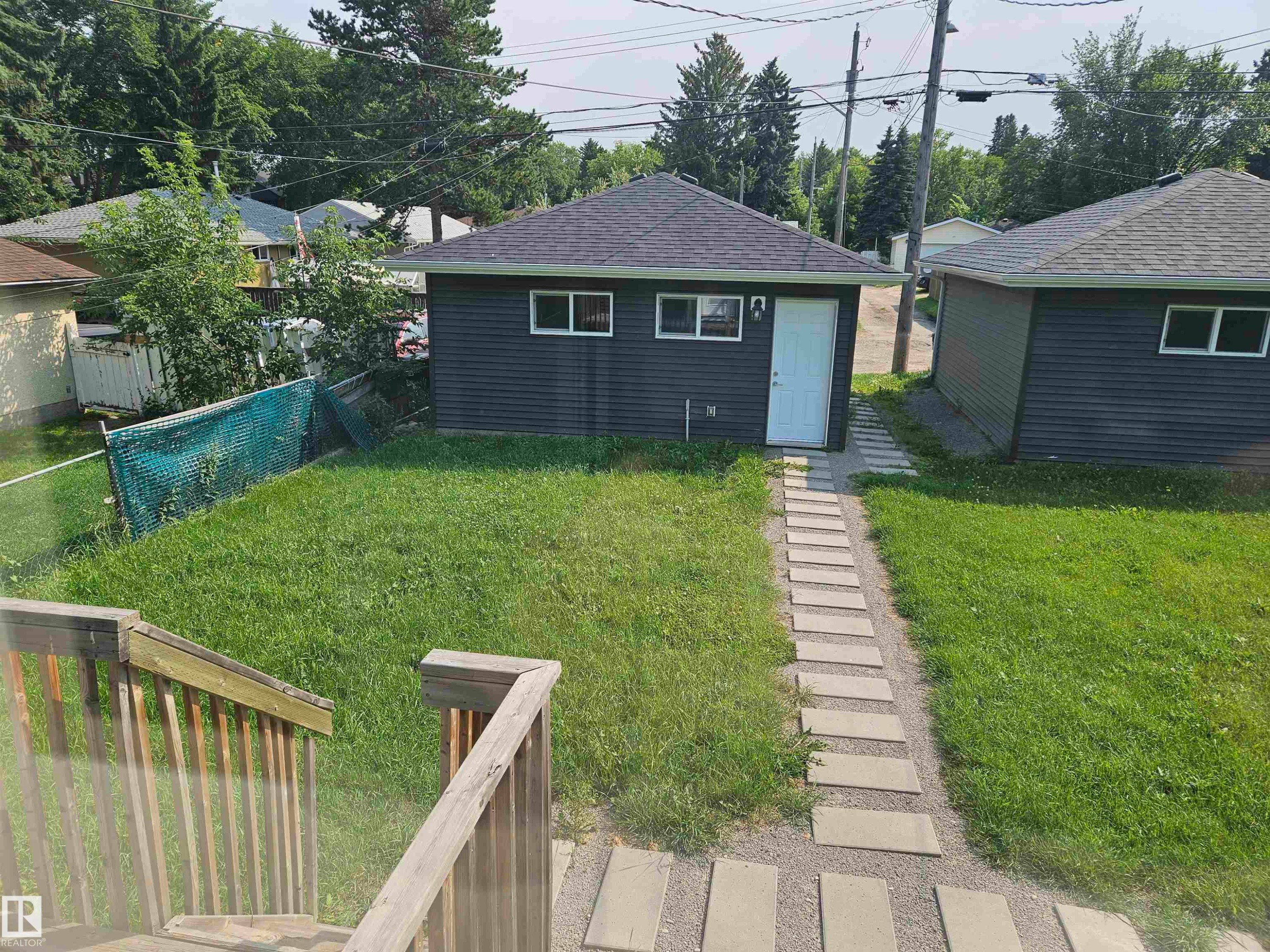 Two separate dark-paneled outbuildings with white trim windows and white entry doors - 9311 66 Avenue Nw, Edmonton, AB - Outdoor