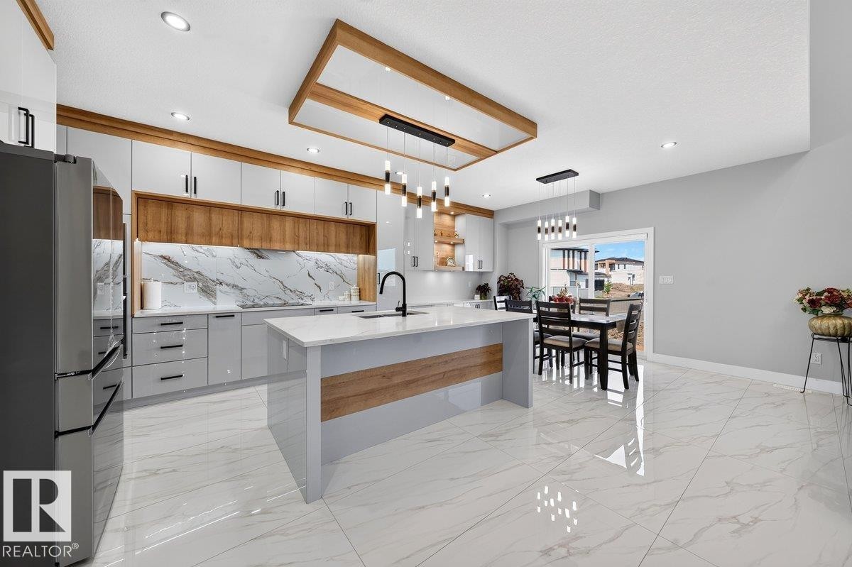 Modern kitchen featuring white high-gloss cabinetry, wood-finish accents, and a large central island with a waterfall countertop - 6001 19 Street, Nisku, AB - Indoor Photo Showing Kitchen With Upgraded Kitchen