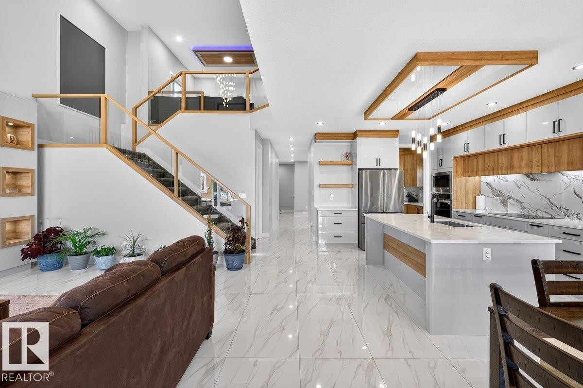 Open-concept interior featuring large-format tile flooring, a contemporary staircase with glass railing, and a gourmet kitchen - 6001 19 Street, Nisku, AB - Indoor