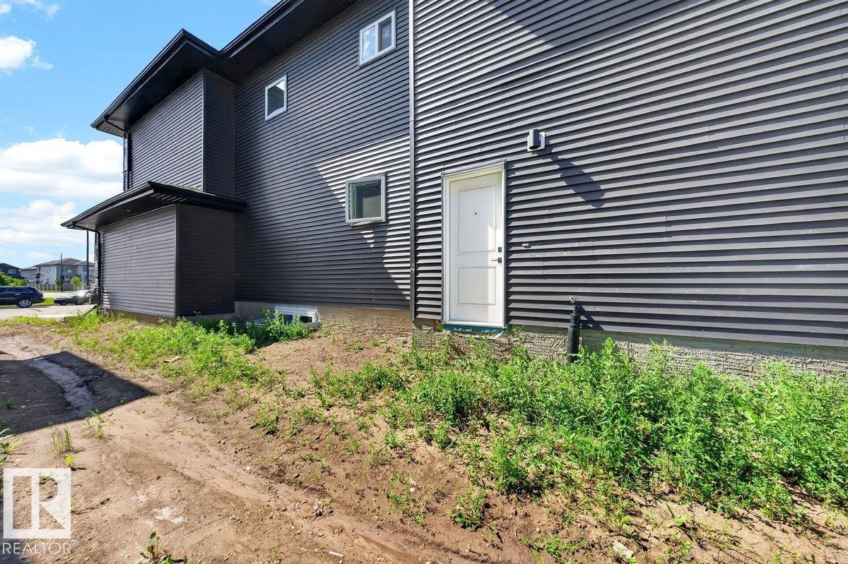 Contemporary dark gray horizontal siding exterior with contrasting white entry door - 6001 19 Street, Nisku, AB - Outdoor