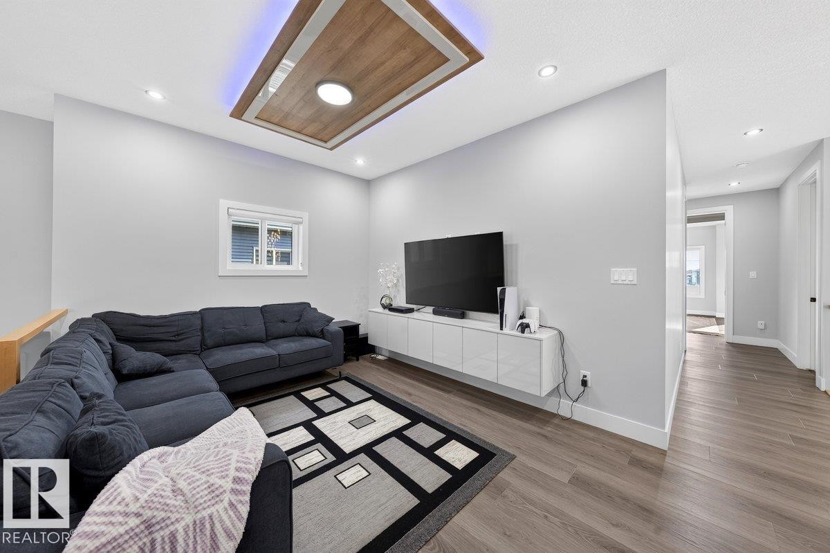 Living area featuring wood-finish flooring, recessed lighting, and a tray ceiling with integrated lighting - 6001 19 Street, Nisku, AB - Indoor Photo Showing Living Room