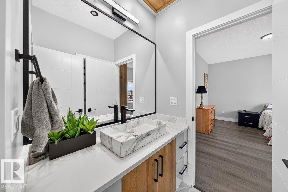 Modern bathroom featuring a rectangular vessel sink with a marble-effect finish, a matte black faucet, and a large wall-mounted mirror - 6001 19 Street, Nisku, AB - Indoor Photo Showing Bathroom