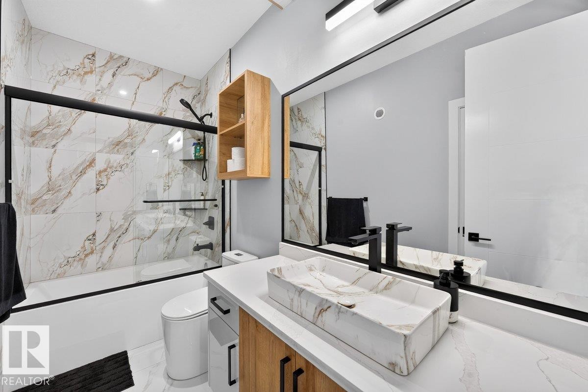 Contemporary bathroom featuring a rectangular vessel sink with a marbling pattern, a black wall-mounted faucet, and a large vanity mirror - 6001 19 Street, Nisku, AB - Indoor