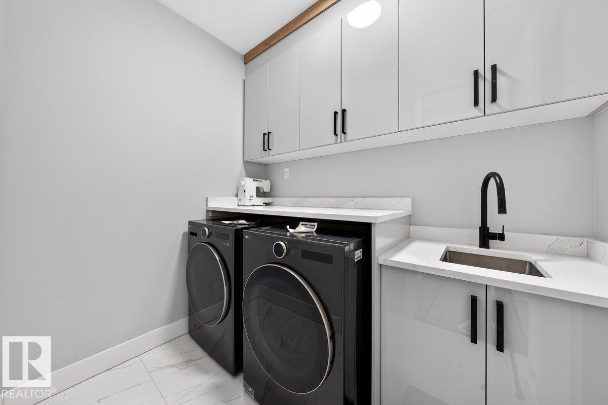 Utility area featuring light grey cabinetry with black hardware, white countertops, a stainless steel sink with a matte black faucet, and white tile flooring - 6001 19 Street, Nisku, AB - Indoor Photo Showing Laundry Room
