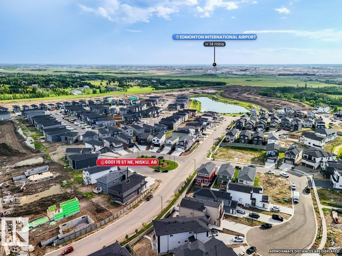Aerial perspective showcasing the residential community with a central pond feature - 6001 19 Street, Nisku, AB - Outdoor With View