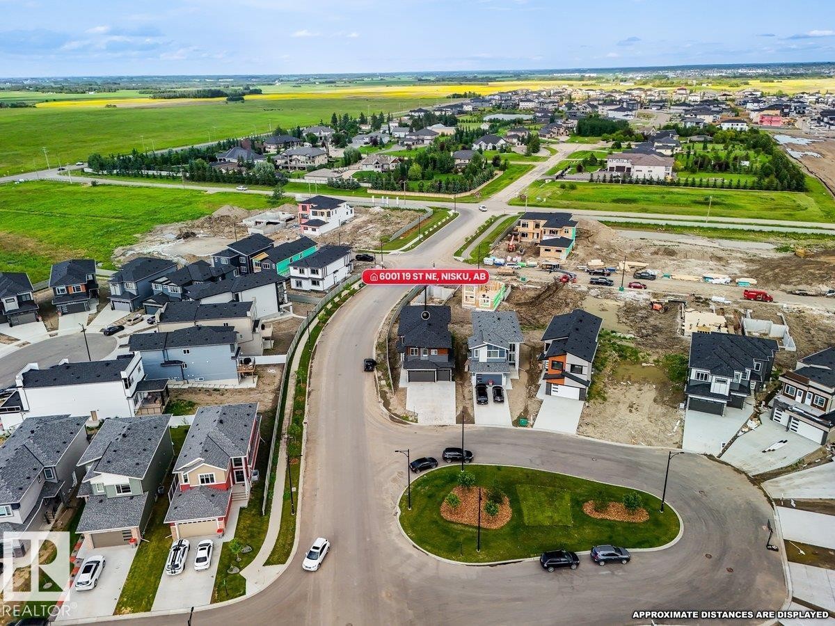 Aerial perspective of a developing residential area with established homes and ongoing construction, surrounded by open green fields - 6001 19 Street, Nisku, AB - Outdoor With View