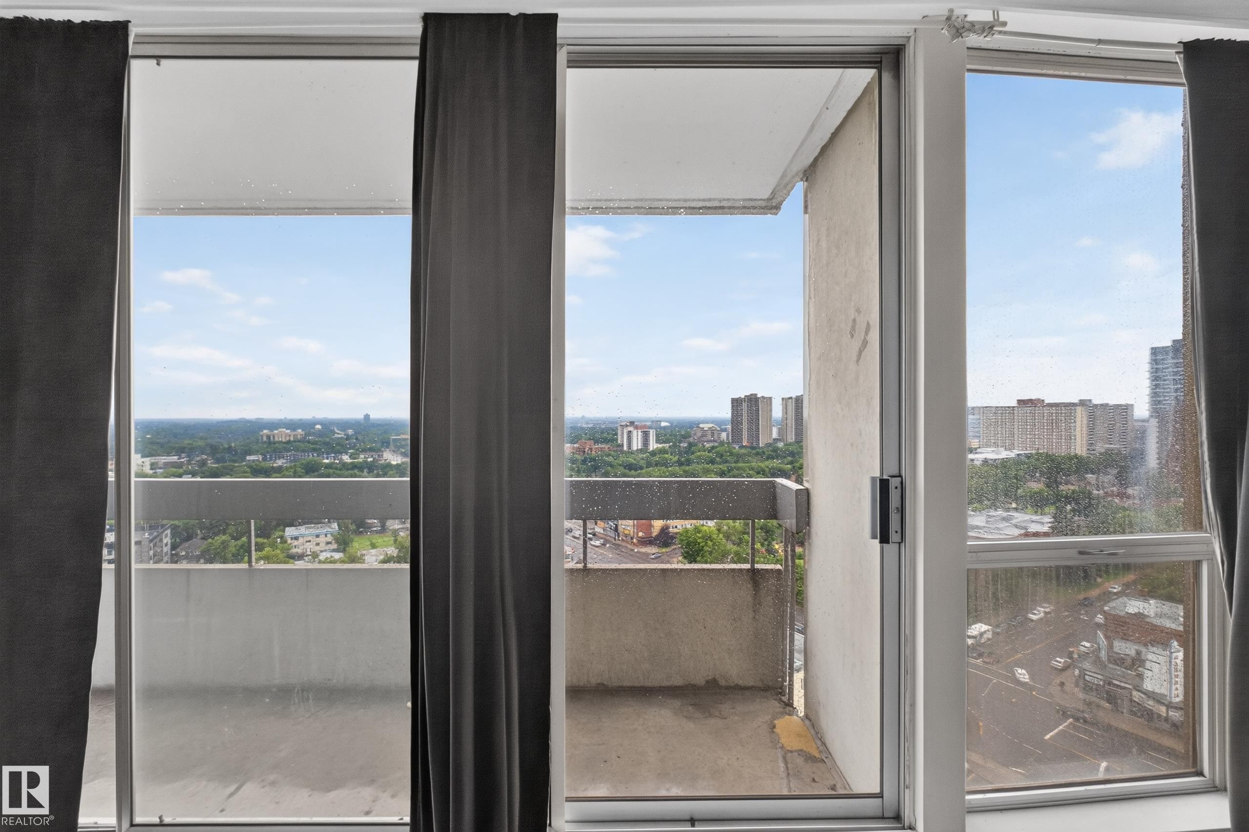 Sliding glass door balcony access featuring a concrete railing and urban landscape - #1804 10883 Saskatchewan Dr Nw, Edmonton, AB - Indoor Photo Showing Other Room