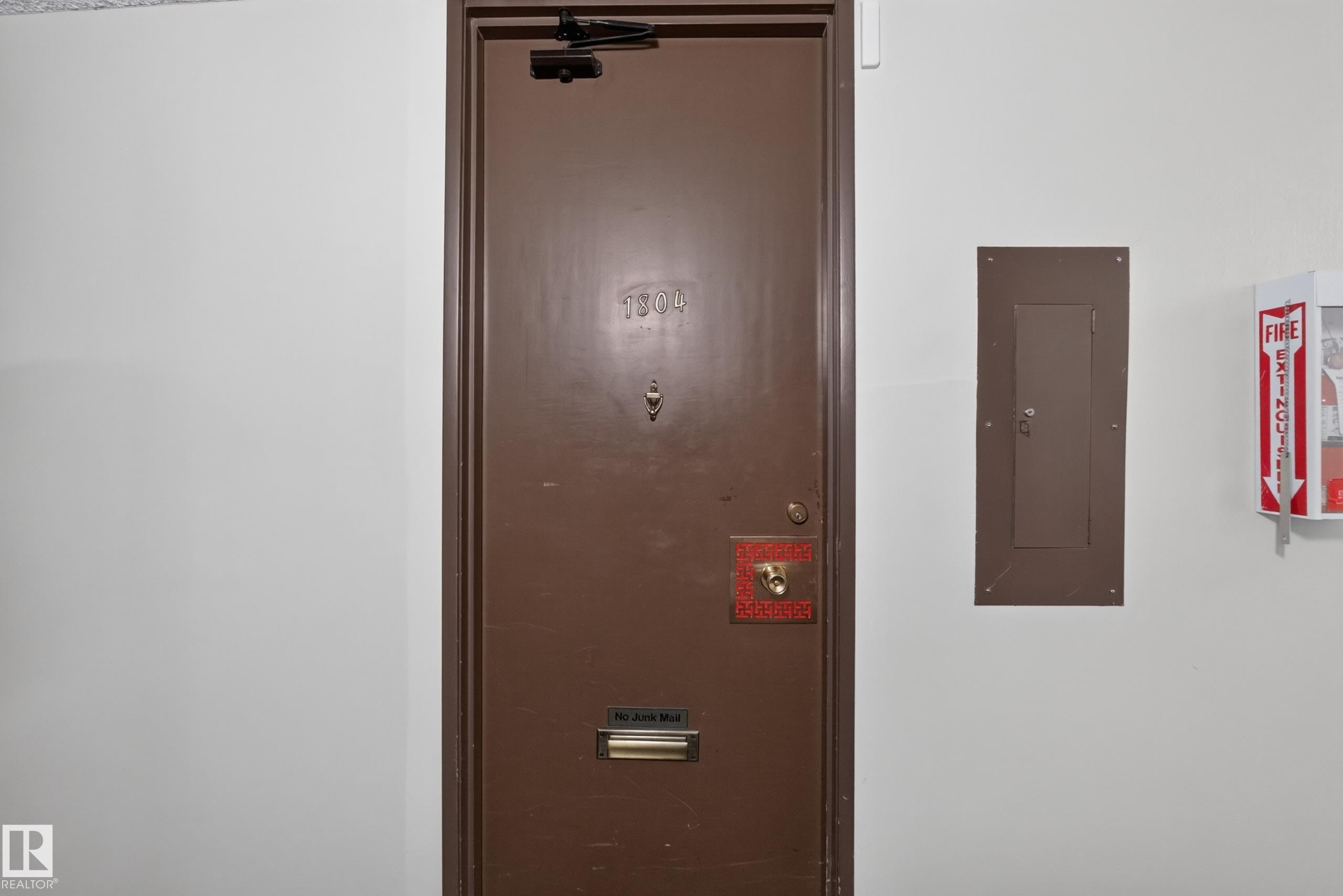 Brown entry door with an overhead door closer, numerical address, mail slot, and an additional security feature - #1804 10883 Saskatchewan Dr Nw, Edmonton, AB - Indoor Photo Showing Other Room