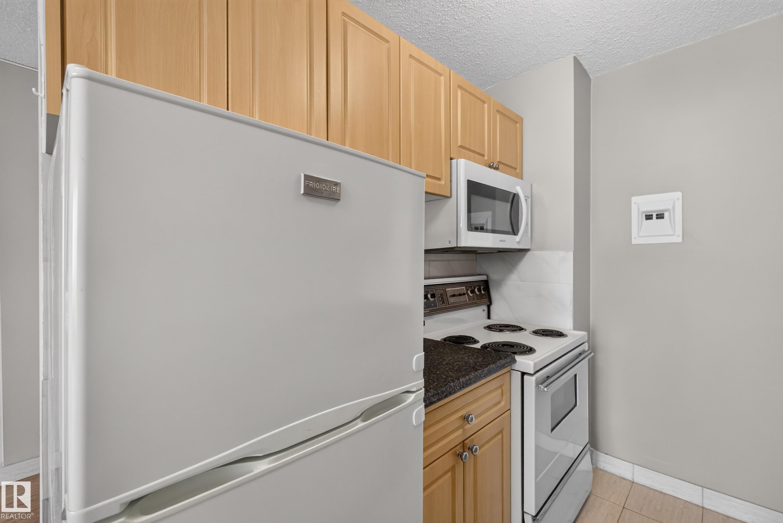 Compact kitchen featuring a full-size refrigerator, electric range with oven, and a built-in microwave - #1508 10883 Saskatchewan Dr Nw Nw, Edmonton, AB - Indoor Photo Showing Kitchen
