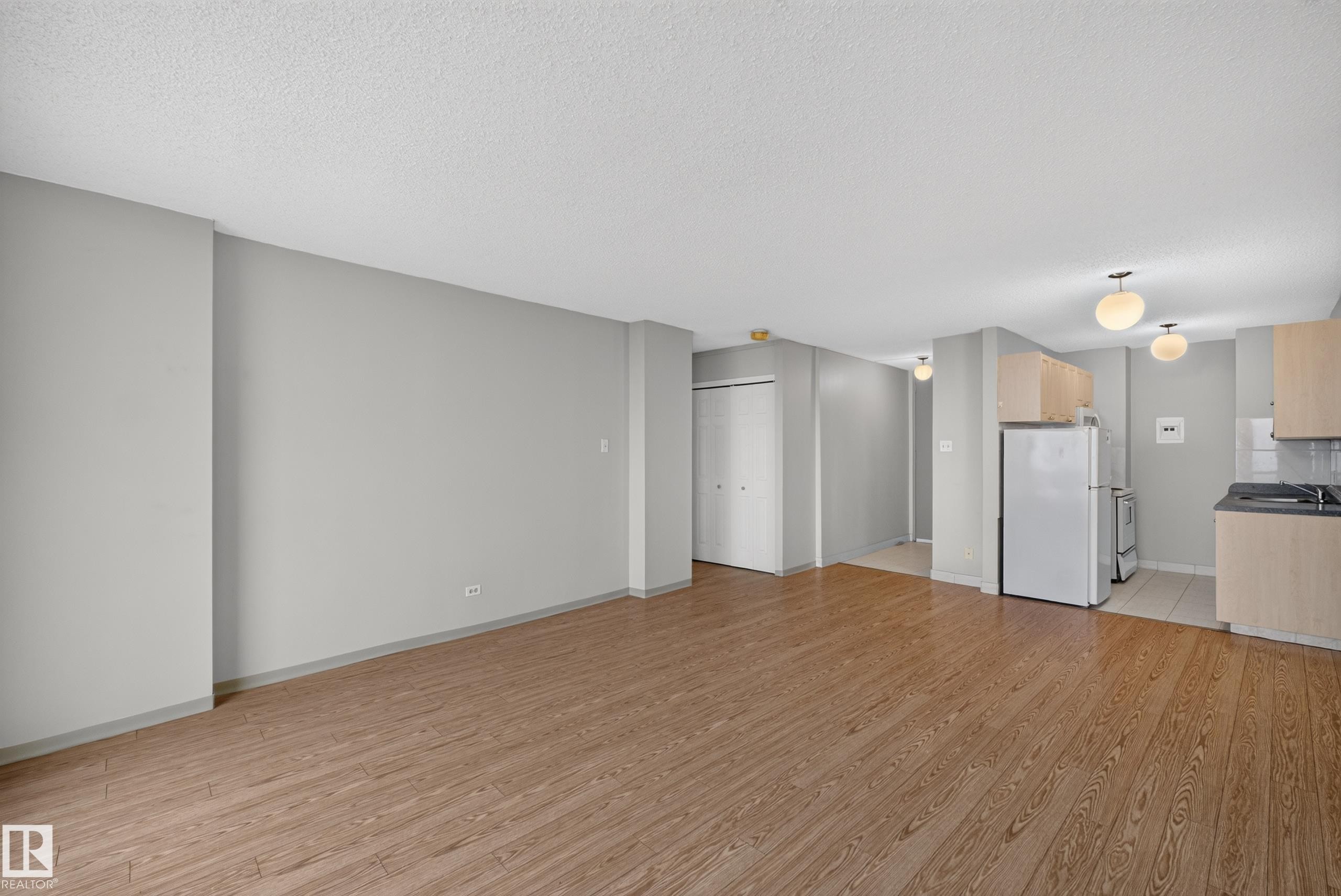 Open-concept living area featuring wood-finish flooring, light gray wall paint, and a textured white ceiling - #1508 10883 Saskatchewan Dr Nw Nw, Edmonton, AB - Indoor Photo Showing Kitchen