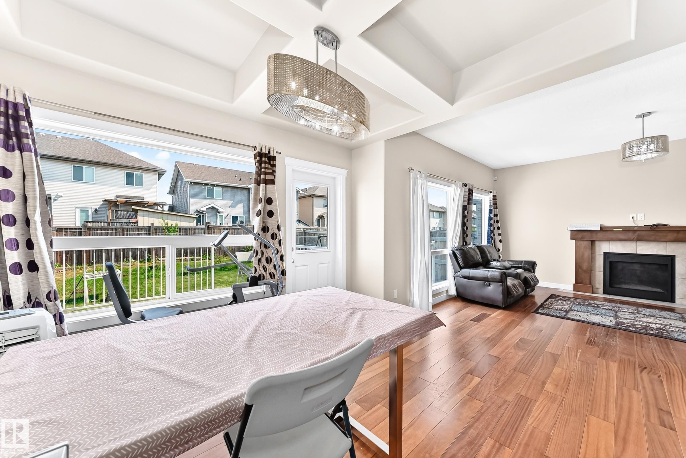 Bright open concept interior featuring wood-finish flooring, a tray ceiling, and a prominent fireplace with a wood mantle - 2923 16 Street Nw, Edmonton, AB - Indoor With Fireplace
