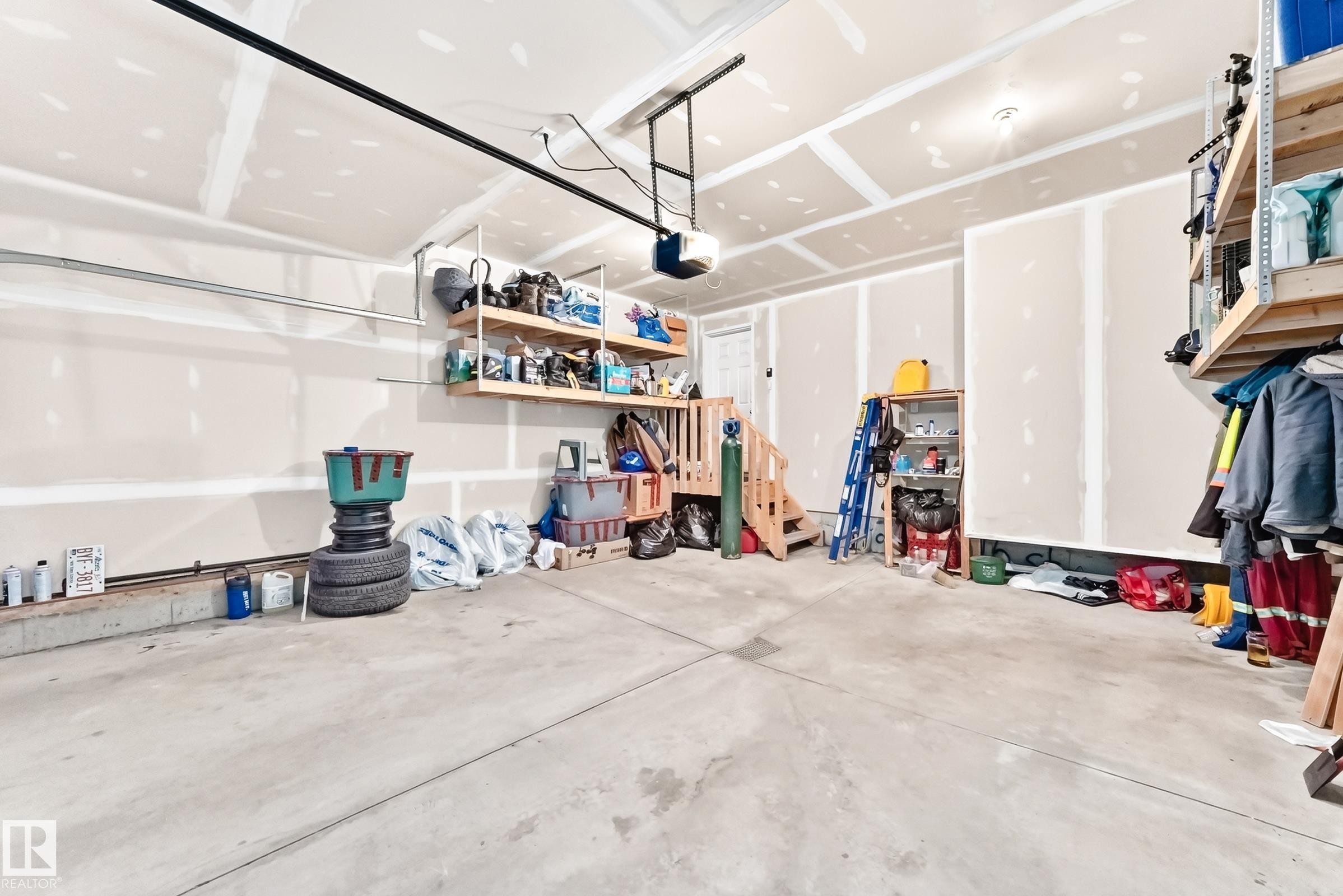 Spacious garage featuring a concrete floor, exposed drywall, and an overhead garage door opener - 2923 16 Street Nw, Edmonton, AB - Indoor Photo Showing Garage
