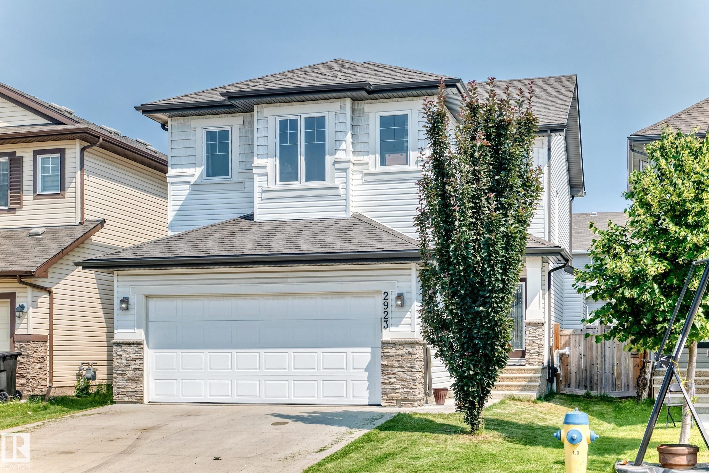 Two-story residence featuring white siding, a dark shingle roof, and a single-car garage with a panel door - 2923 16 Street Nw, Edmonton, AB - Outdoor With Facade