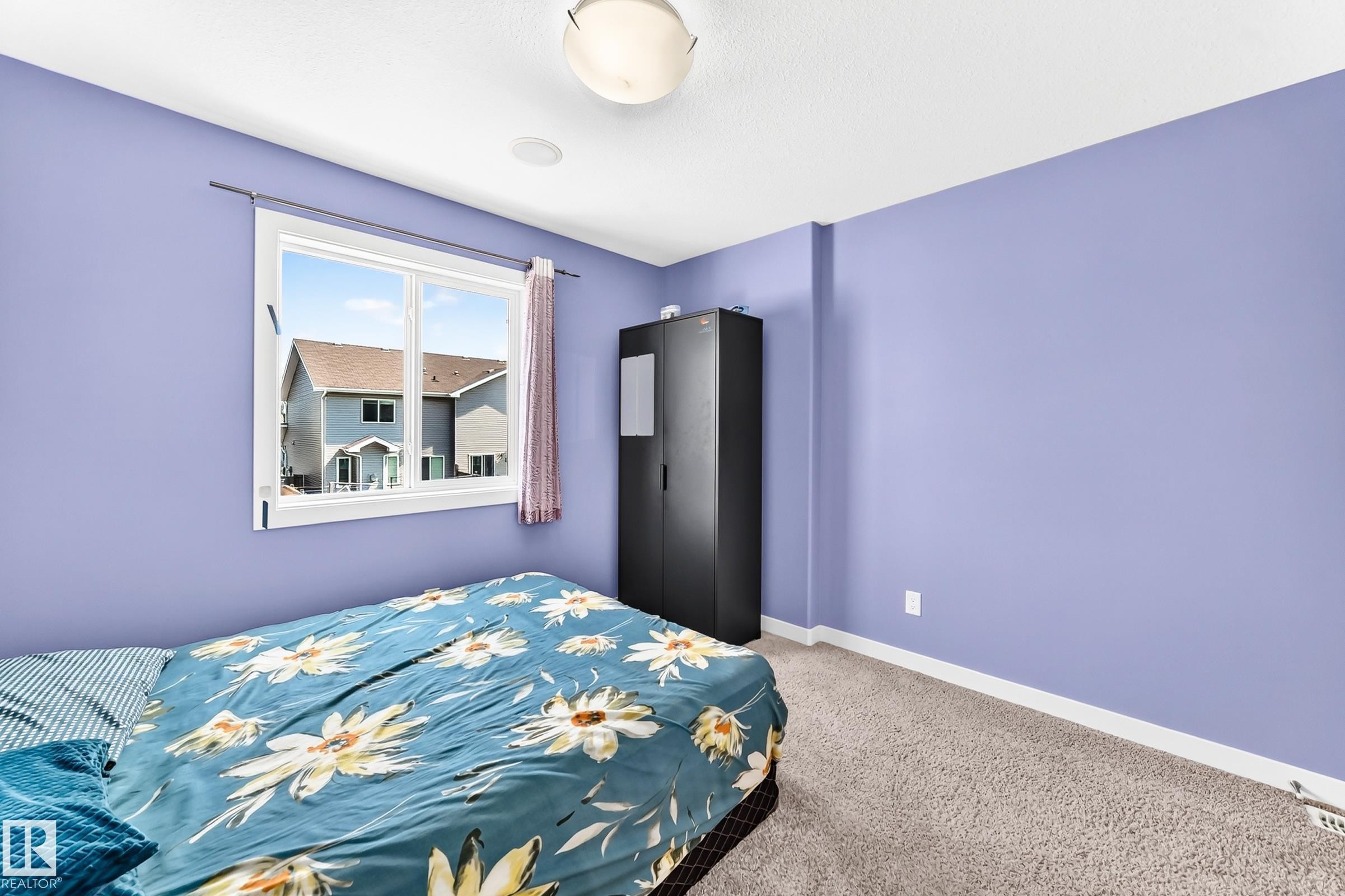 Carpeted room featuring a white-framed window, flush-mount ceiling light fixture, and white baseboards - 2923 16 Street Nw, Edmonton, AB - Indoor Photo Showing Bedroom