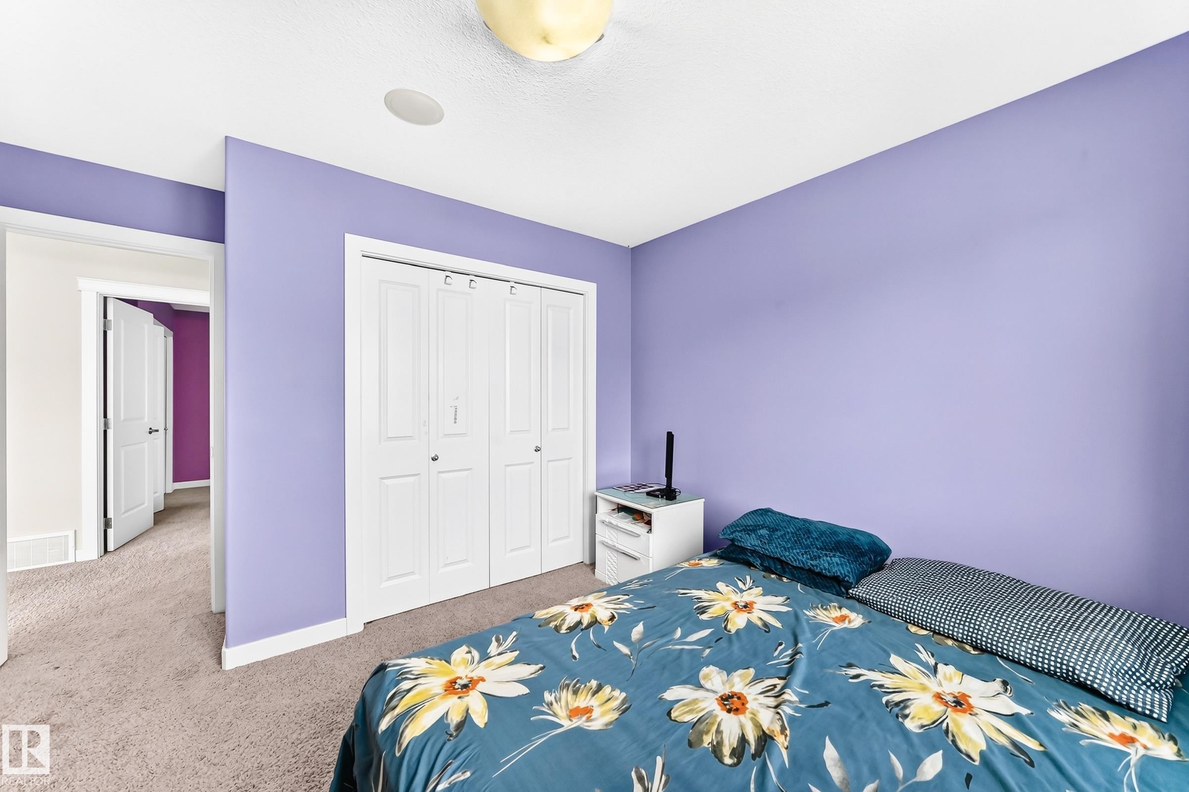 Bedroom featuring a built-in closet with bi-fold doors, white trim, and light-colored carpet flooring - 2923 16 Street Nw, Edmonton, AB - Indoor Photo Showing Bedroom