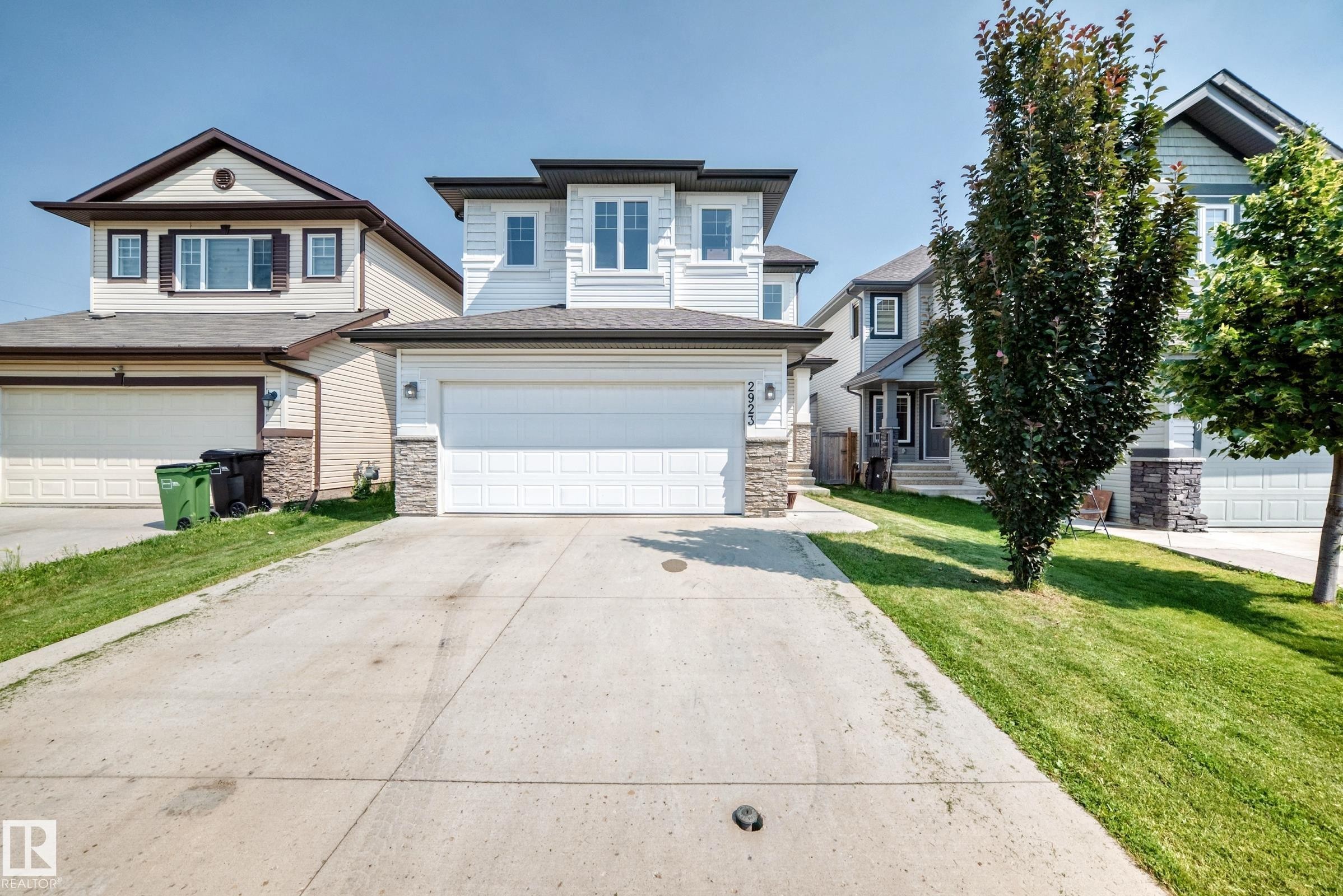 Modern home exterior featuring light-toned siding with dark trim accents and stone veneer detailing - 2923 16 Street Nw, Edmonton, AB - Outdoor With Facade