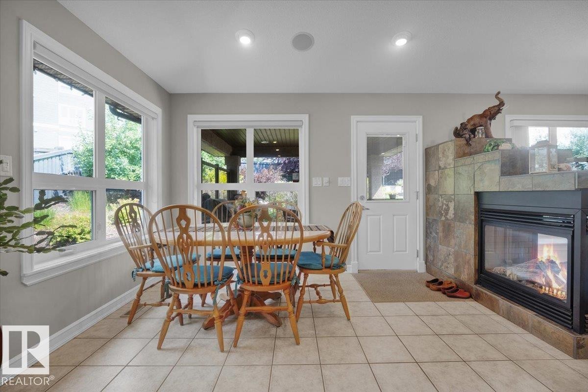 Tile flooring extends through this room, featuring a built-in fireplace with a stone surround - 928 Thompson Place Nw, Edmonton, AB - Indoor Photo Showing Dining Room With Fireplace
