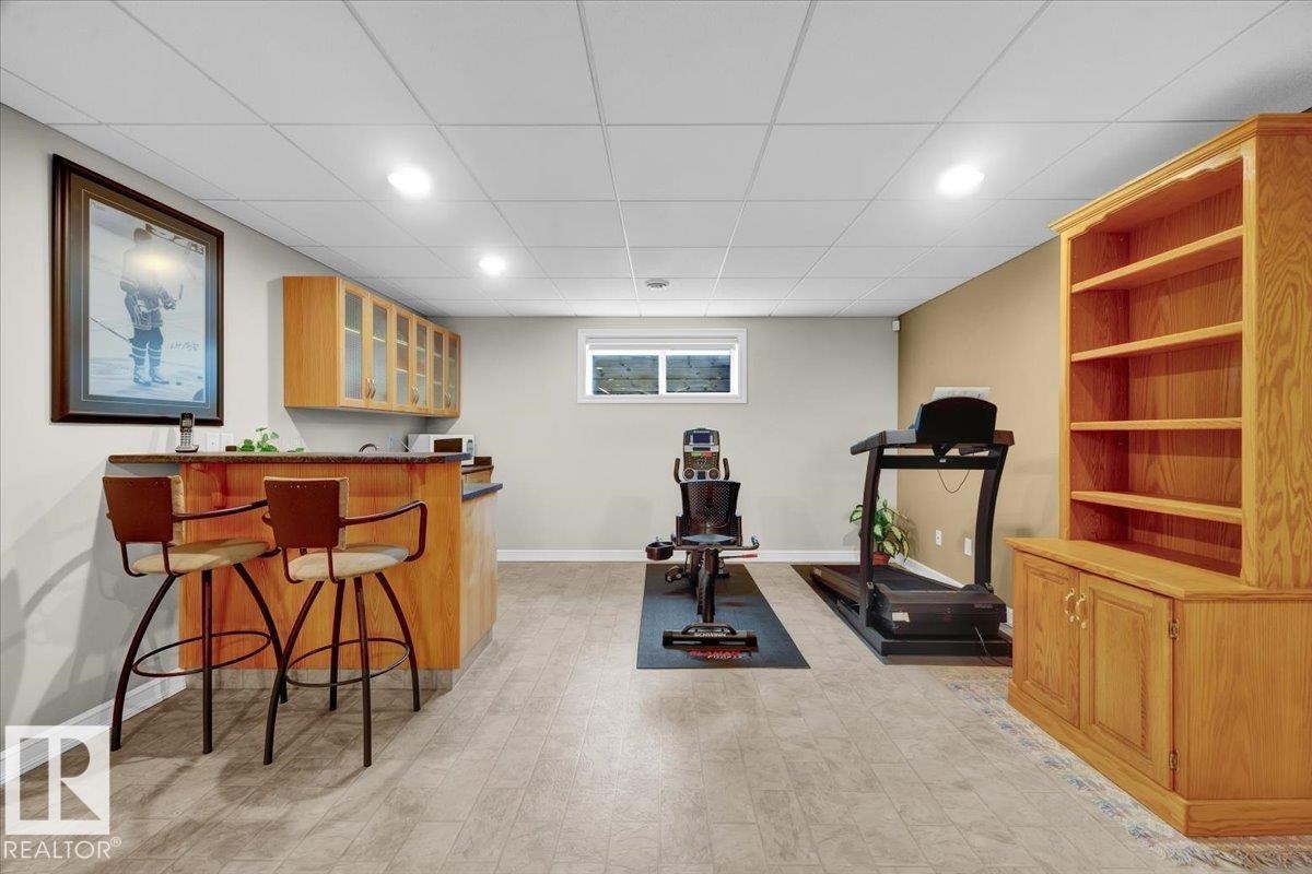 Finished lower level featuring a wet bar with wood-finish cabinetry, recessed lighting, and light-tone flooring - 928 Thompson Place Nw, Edmonton, AB - Indoor Photo Showing Other Room