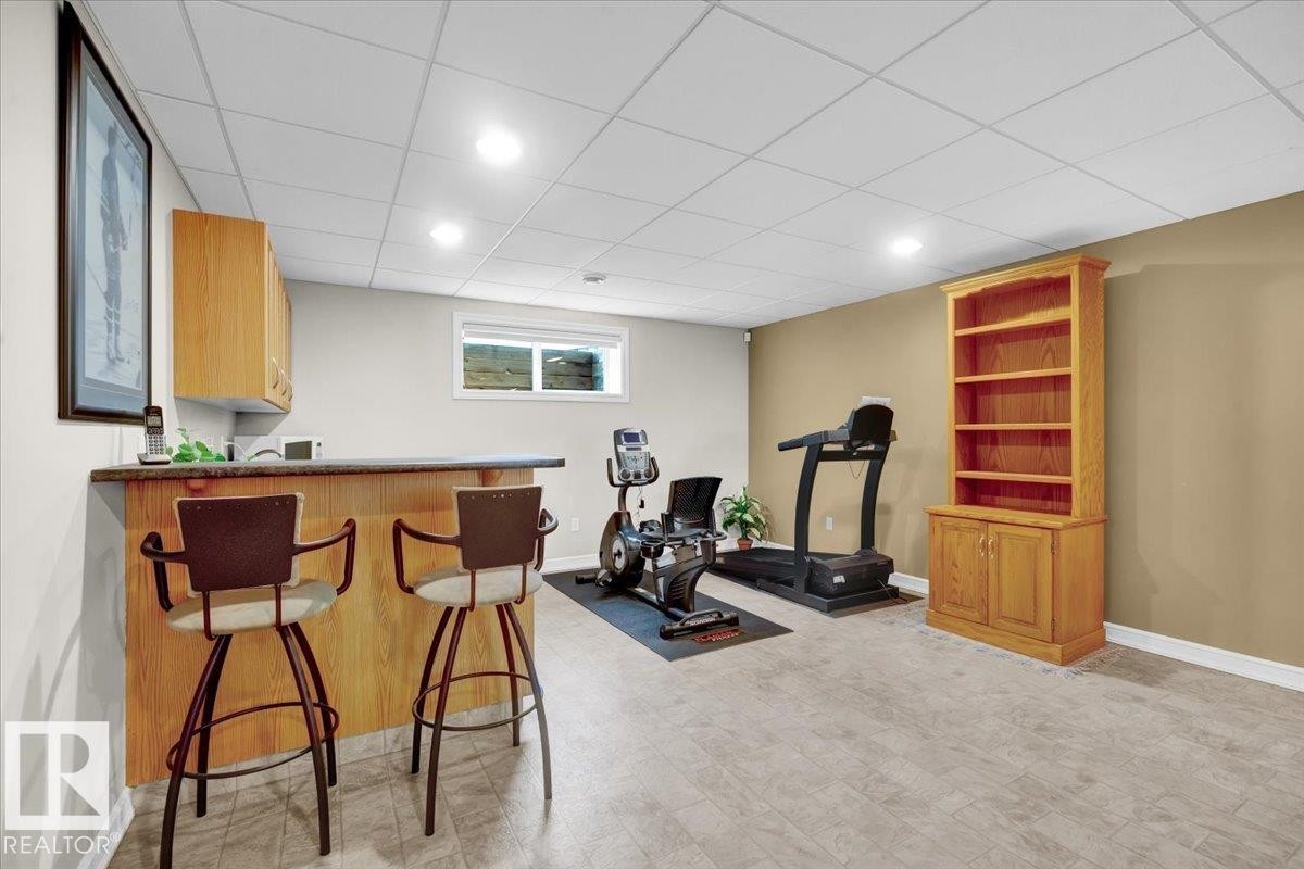Finished lower level featuring a built-in bar with wood cabinetry and countertop, recessed lighting, and durable flooring - 928 Thompson Place Nw, Edmonton, AB - Indoor