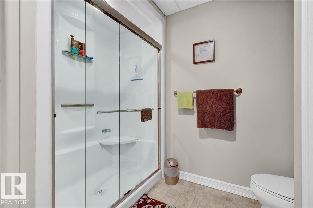 White acrylic shower enclosure with sliding glass doors, integrated shelving, and a built-in corner seat - 928 Thompson Place Nw, Edmonton, AB - Indoor Photo Showing Bathroom