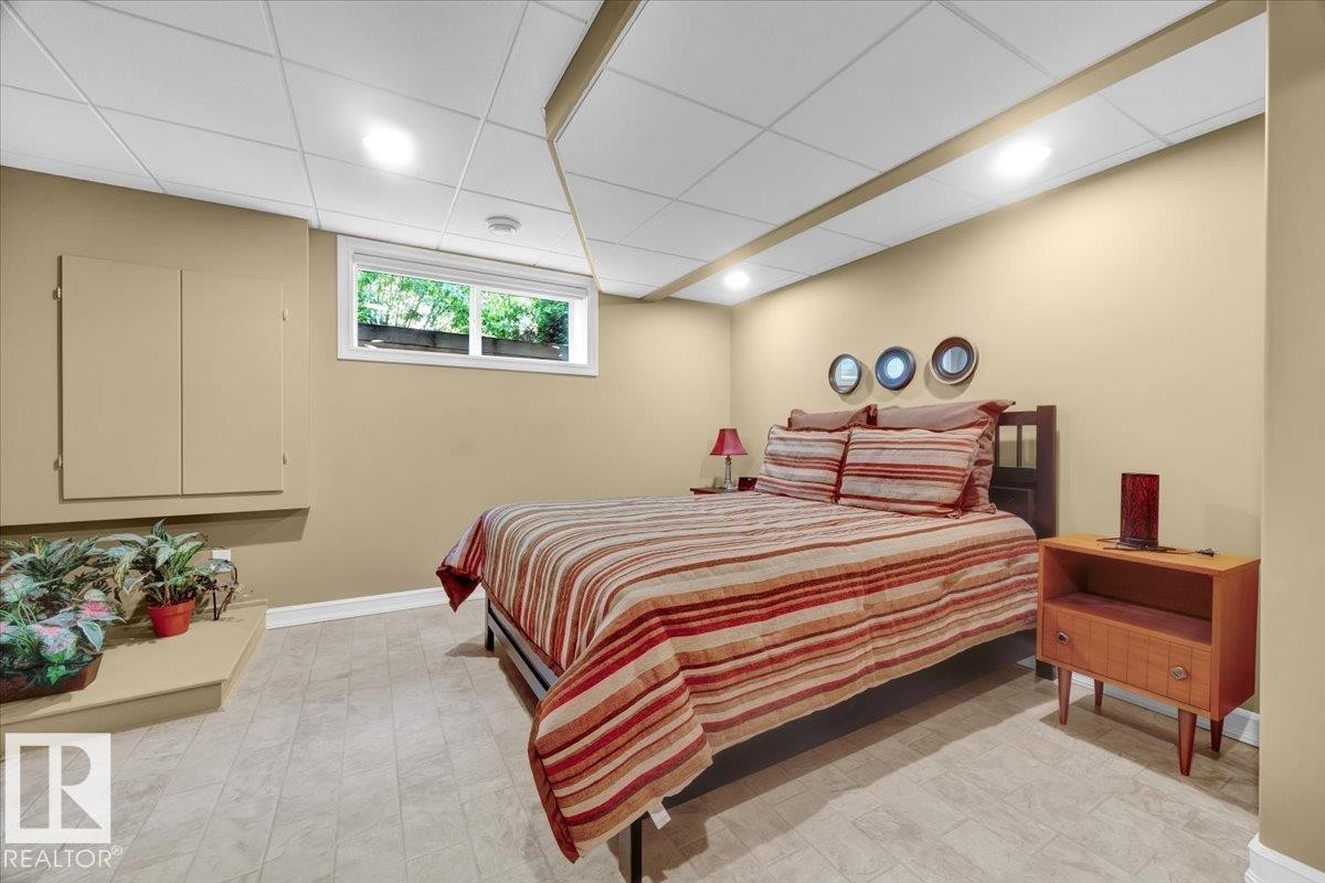 Recessed lighting illuminating a dropped ceiling, a window providing exterior light, light-toned wall paint, and a built-in storage cabinet - 928 Thompson Place Nw, Edmonton, AB - Indoor Photo Showing Bedroom