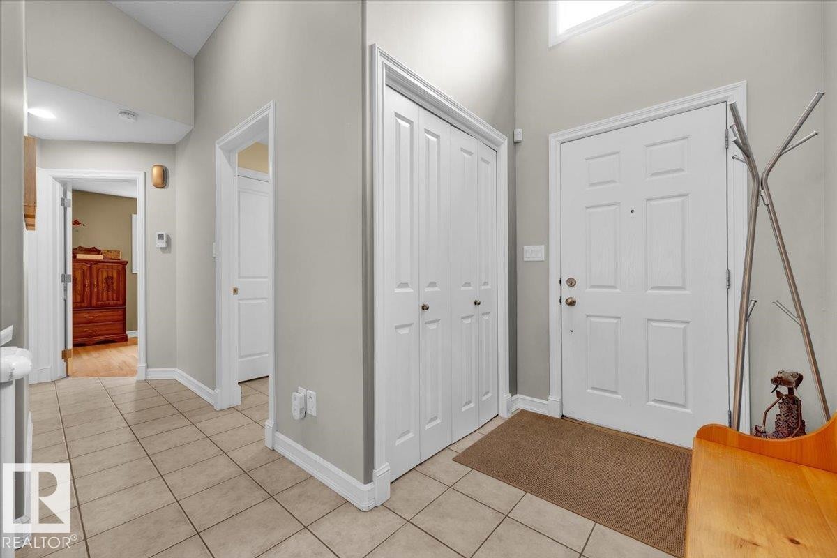 Foyer featuring tiled flooring, a paneled entry door, bi-fold closet doors, and light gray wall paint - 928 Thompson Place Nw, Edmonton, AB - Indoor Photo Showing Other Room