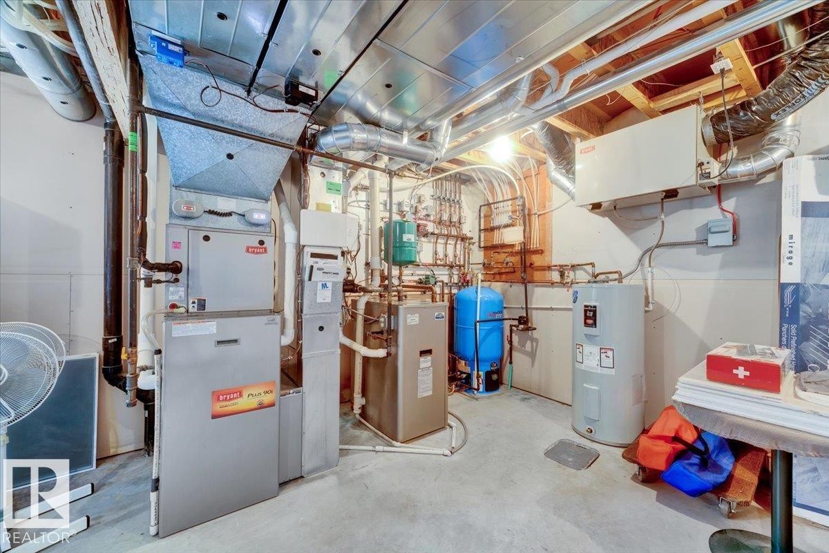 Utility room featuring forced air furnace, hot water heater, water treatment system, and exposed ductwork - 928 Thompson Place Nw, Edmonton, AB - Indoor Photo Showing Basement