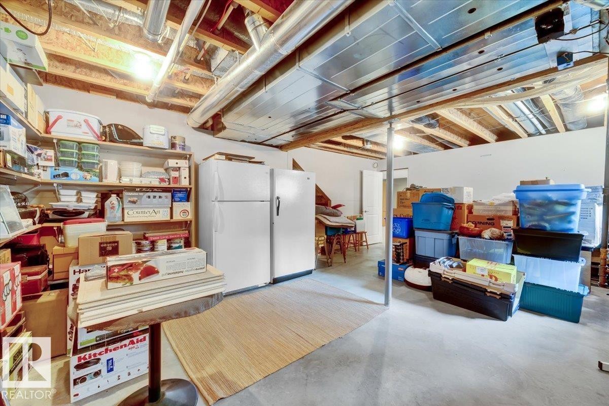 Unfinished basement featuring exposed wood joists and ductwork, concrete flooring, and built-in shelving - 928 Thompson Place Nw, Edmonton, AB - Indoor Photo Showing Basement