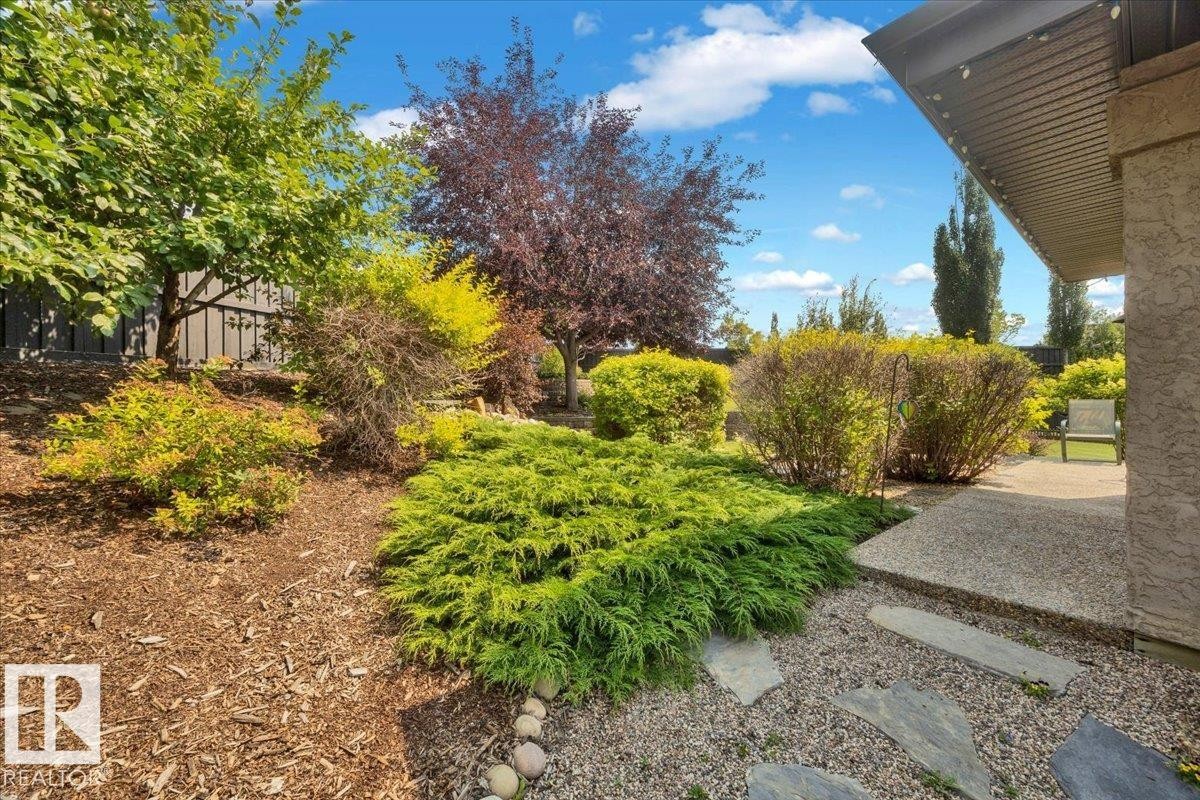 Beautifully landscaped grounds featuring mature trees, ornamental shrubs, and layered plantings throughout the yard - 928 Thompson Place Nw, Edmonton, AB - Outdoor