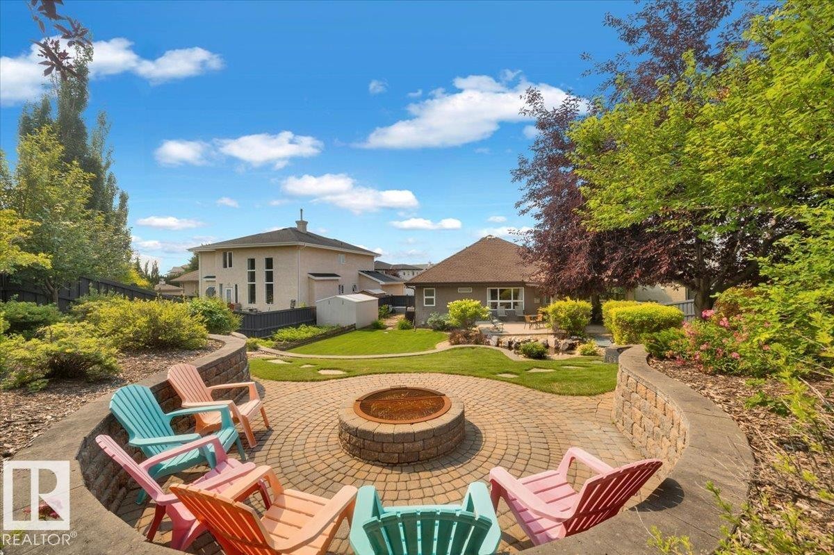 Terraced backyard featuring a paver patio with a built-in fire pit, stone retaining walls, and mature landscaping - 928 Thompson Place Nw, Edmonton, AB - Outdoor With Deck Patio Veranda