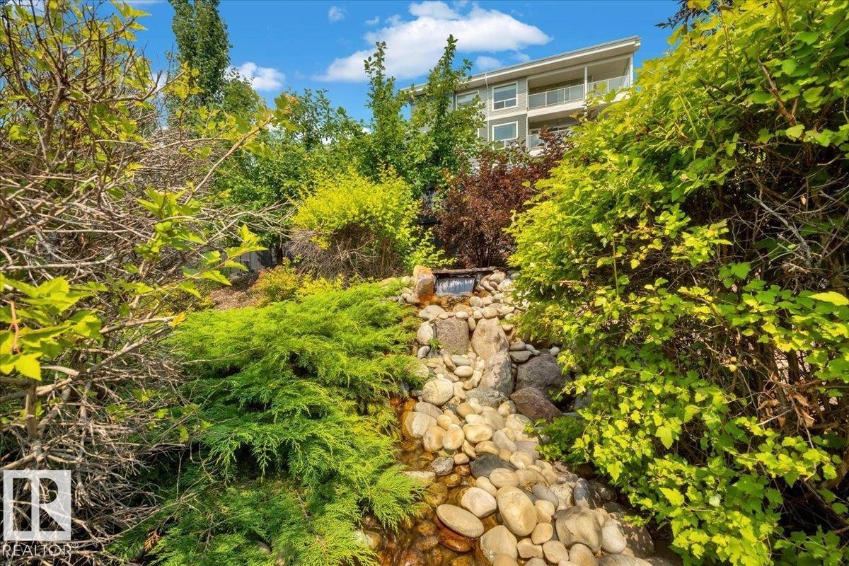 Tiered landscaping featuring a rock-lined stream with a cascading waterfall - 928 Thompson Place Nw, Edmonton, AB - Outdoor