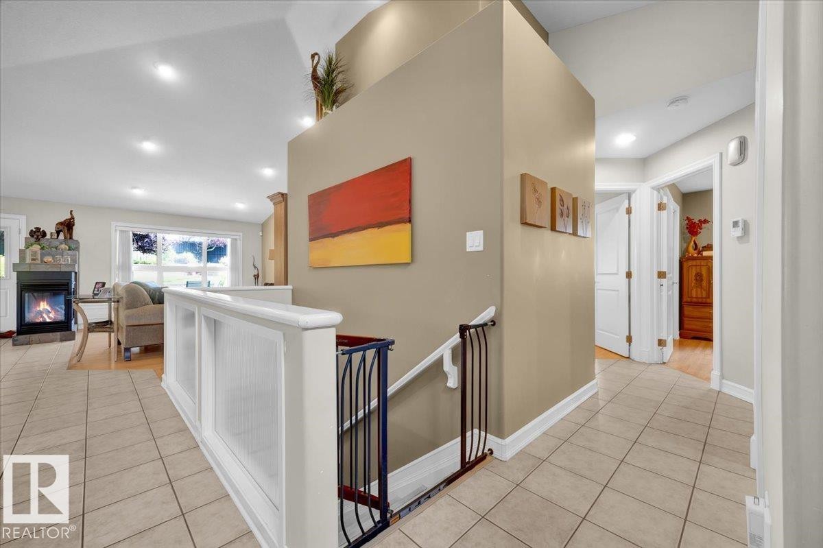 Tiled entryway featuring a white staircase railing with wrought iron balusters, recessed lighting, and a neutral wall color - 928 Thompson Place Nw, Edmonton, AB - Indoor Photo Showing Other Room