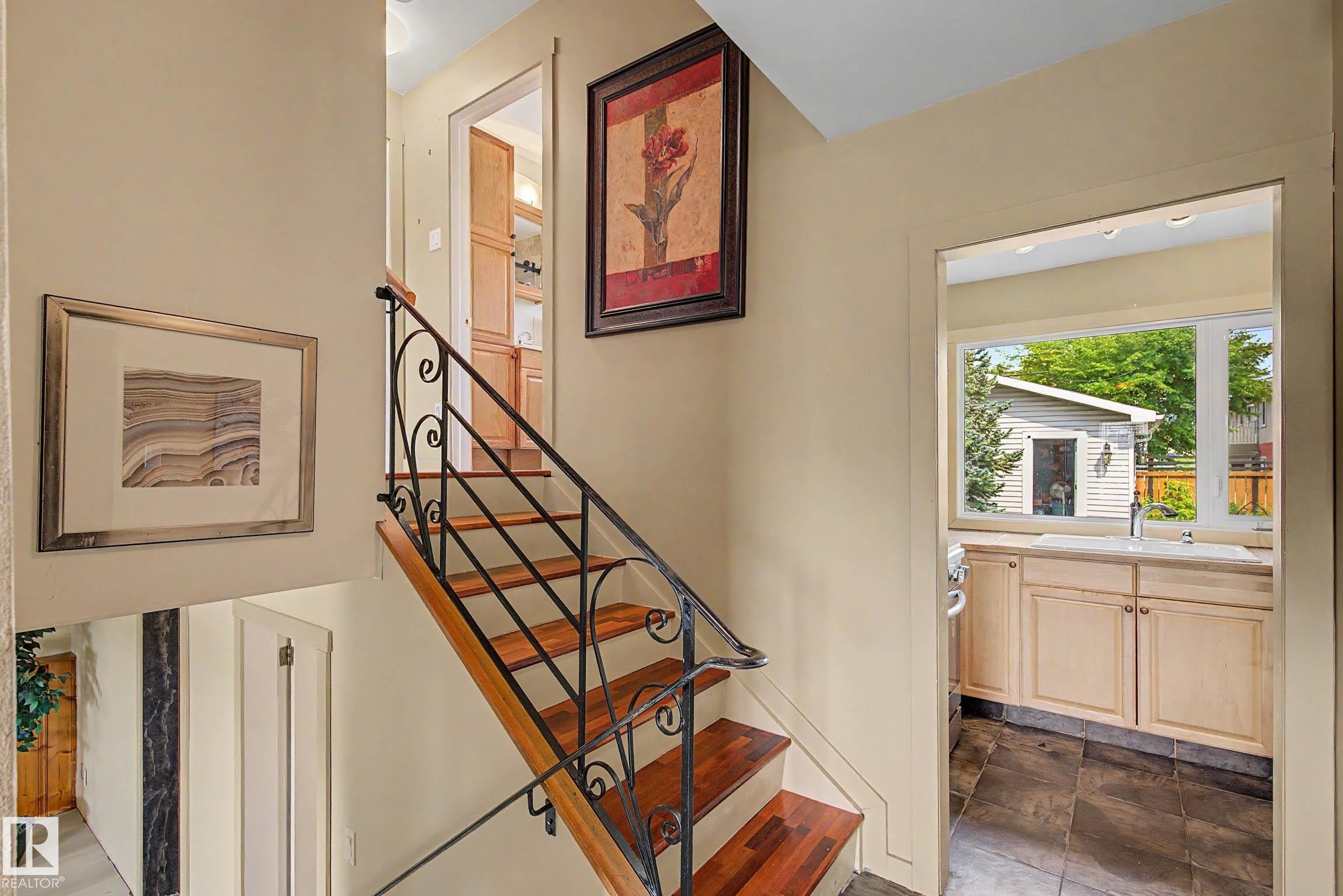 Staircase featuring wood-finish treads and an ornamental wrought iron railing - 9516 129A Avenue Nw, Edmonton, AB