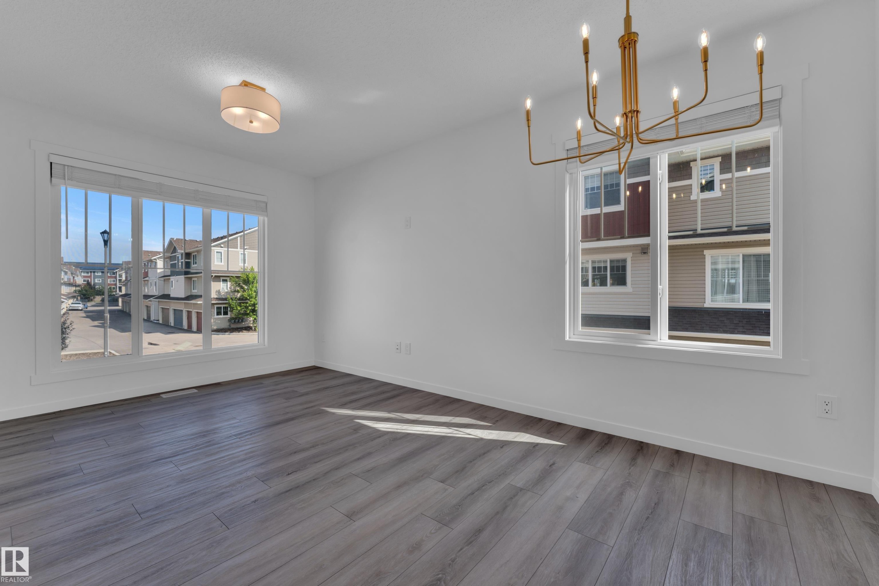 Spacious room featuring light gray wood-finish flooring and white walls - #64 17832 78 St Nw Nw, Edmonton, AB - Indoor Photo Showing Other Room