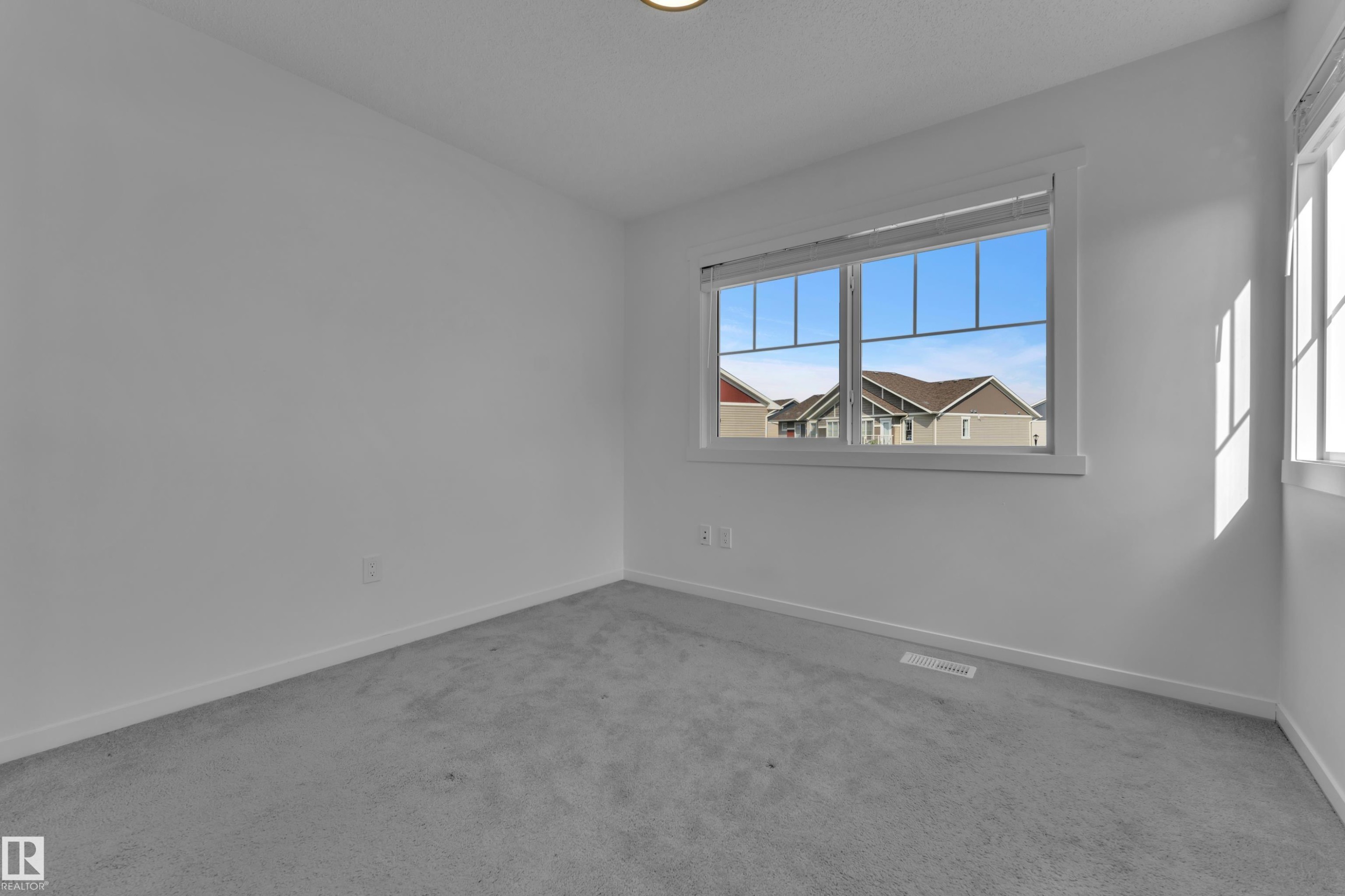 Room featuring light gray carpeting, white walls, and a large window with white trim - #64 17832 78 St Nw Nw, Edmonton, AB - Indoor Photo Showing Other Room