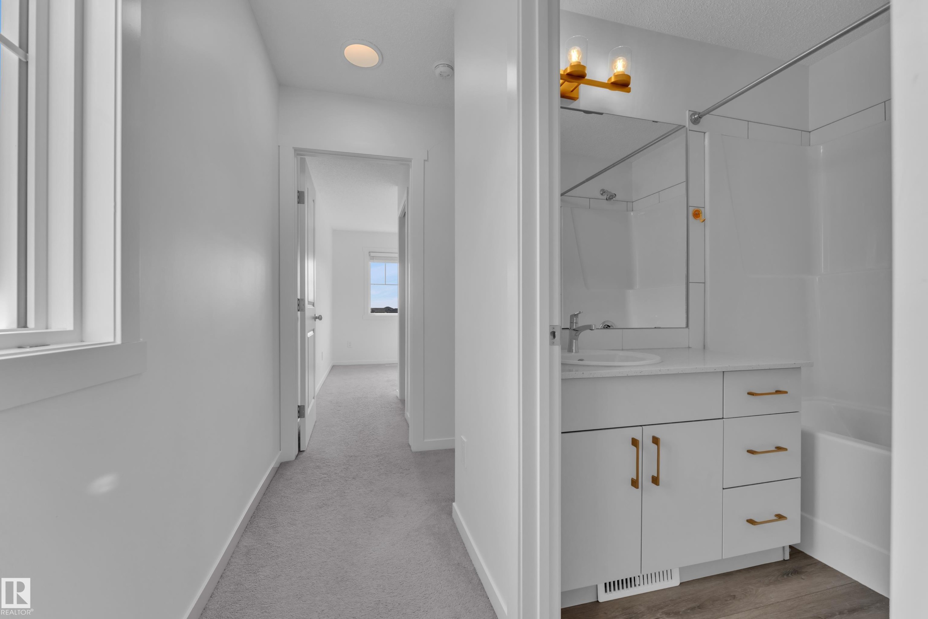 Bright hallway featuring light gray carpeting, recessed lighting, and a window with white trim - #64 17832 78 St Nw Nw, Edmonton, AB - Indoor Photo Showing Other Room