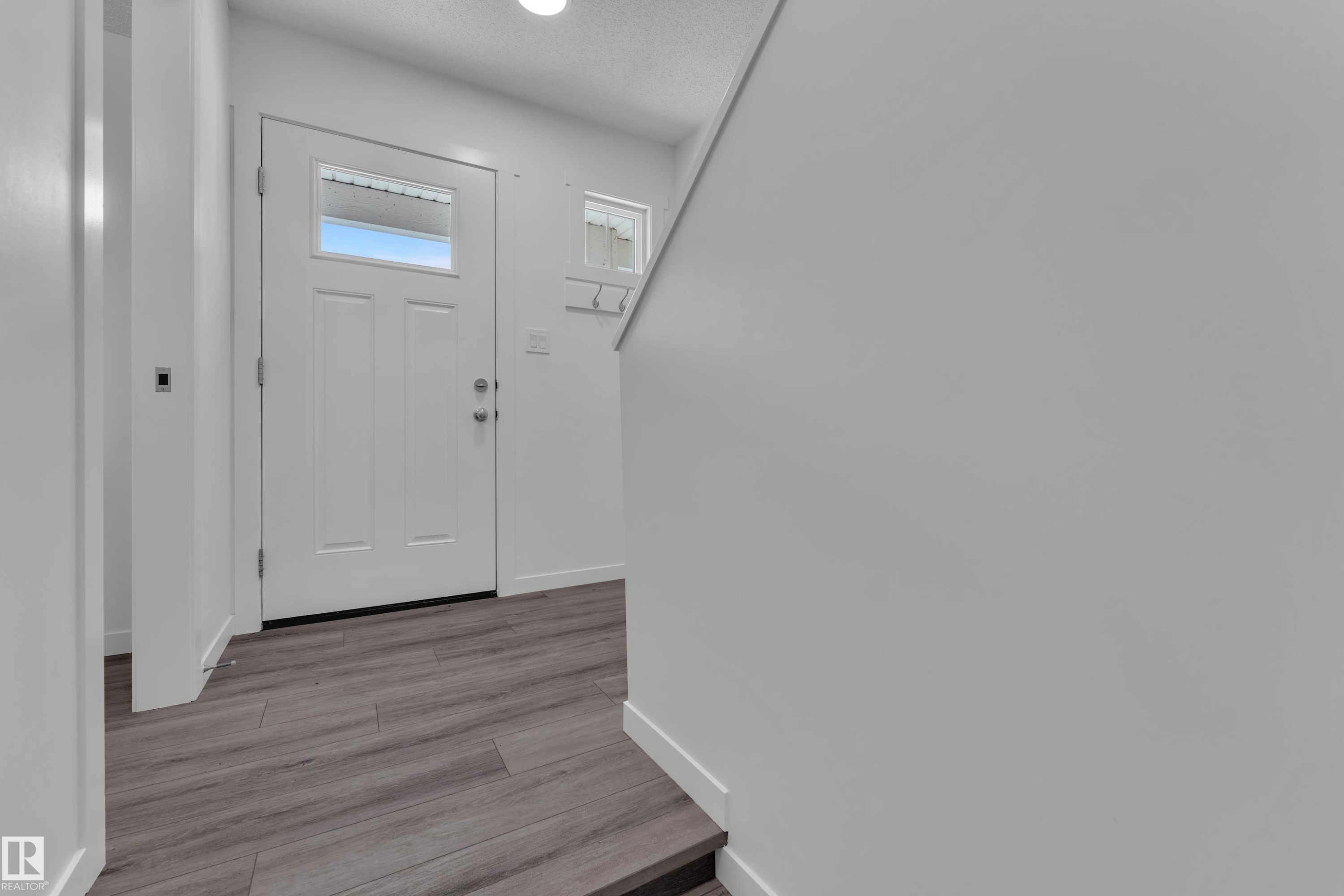 Entryway featuring wood-finish flooring, a white paneled door with an upper window, and a white transom window - #64 17832 78 St Nw Nw, Edmonton, AB - Indoor Photo Showing Other Room