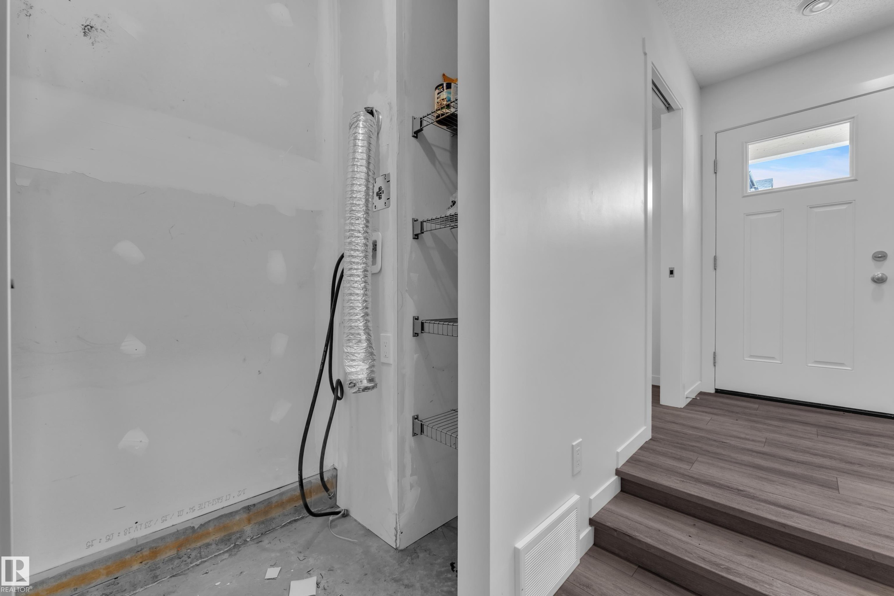 Entryway featuring wood-finish flooring, a white paneled door with an upper window, and integrated shelving - #64 17832 78 St Nw Nw, Edmonton, AB - Indoor Photo Showing Other Room