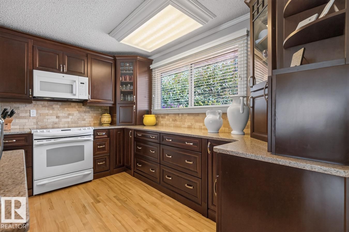Kitchen featuring rich wood cabinetry, light-toned countertops, a full suite of white appliances, and a tiled backsplash - 27 Milford Crescent, Sherwood Park, AB - Indoor Photo Showing Kitchen