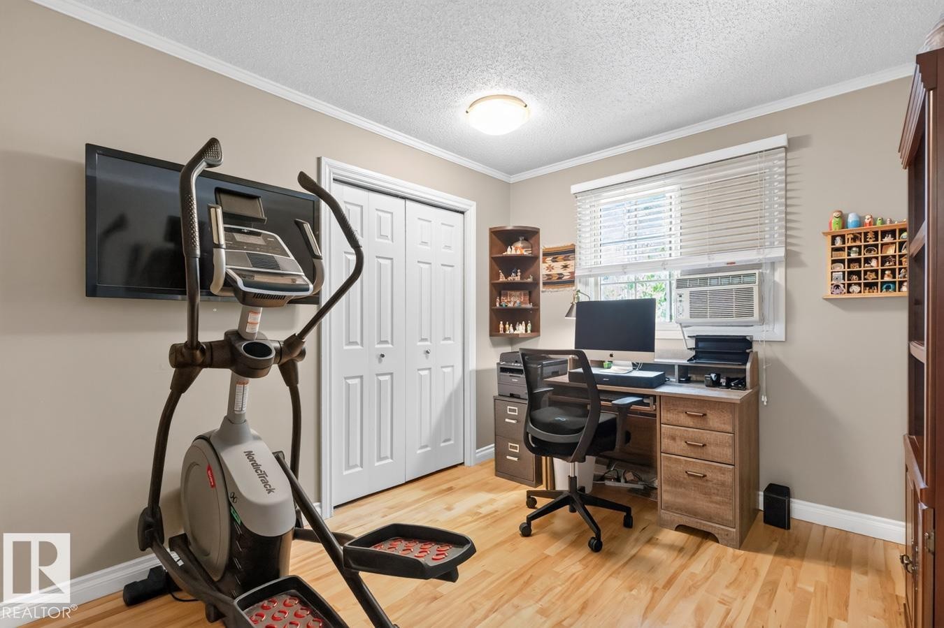 Versatile room featuring wood-finish flooring, a window with horizontal blinds, and a built-in closet with bi-fold doors - 27 Milford Crescent, Sherwood Park, AB - Indoor