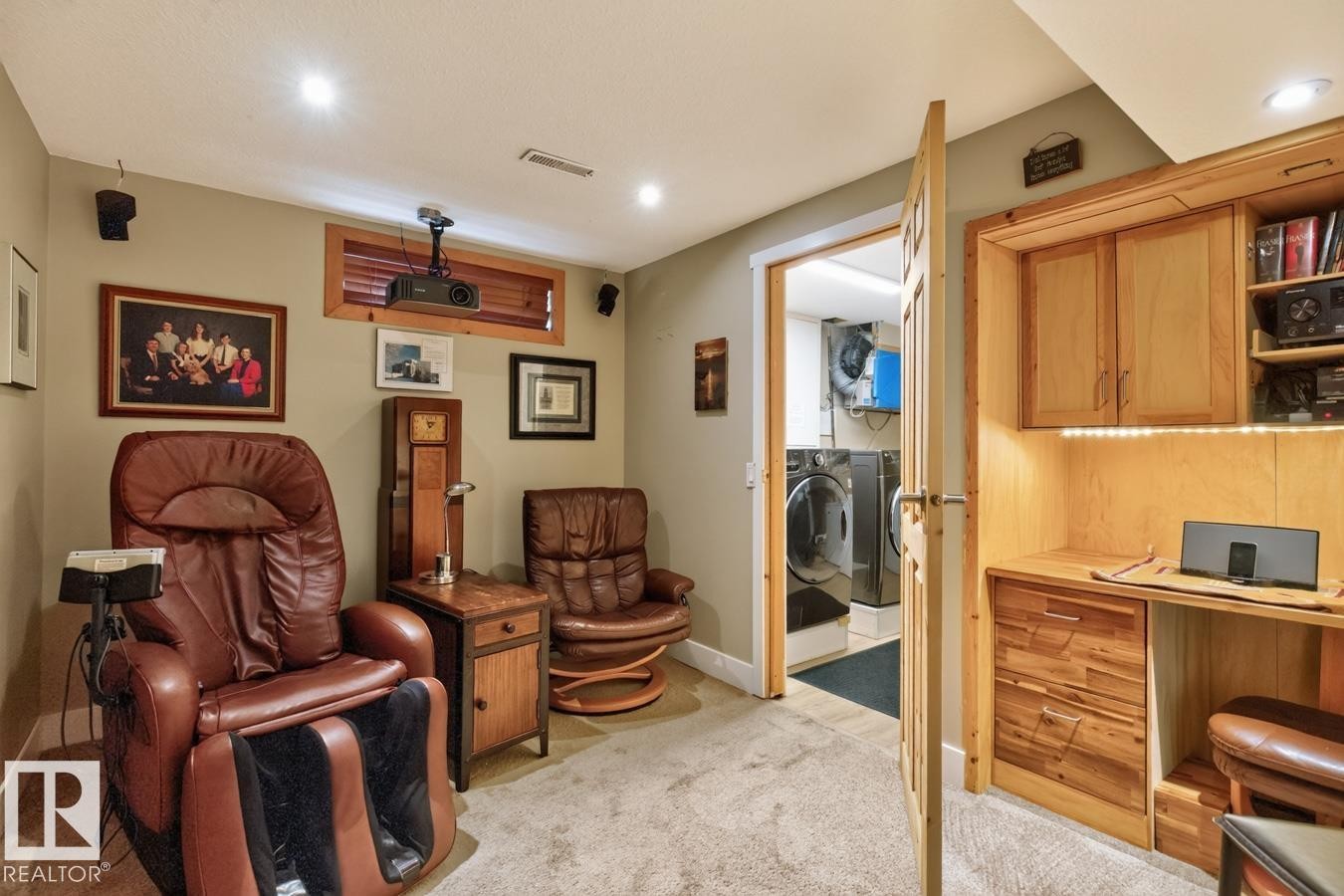 Dedicated media room featuring built-in wood cabinetry with shelving, recessed ceiling lighting, and plush leather seating with integrated footrests - 27 Milford Crescent, Sherwood Park, AB - Indoor