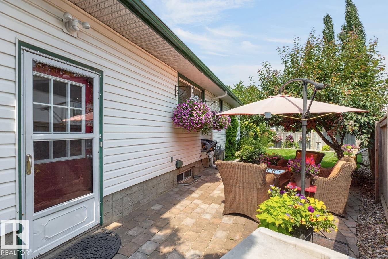 Paved patio area featuring white siding, a grid-paned door, and mature trees - 27 Milford Crescent, Sherwood Park, AB - Outdoor With Deck Patio Veranda With Exterior