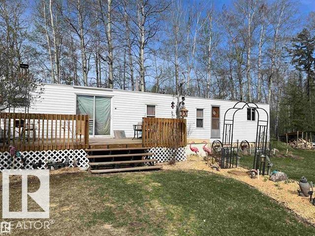 White siding exterior with a large wooden deck featuring a lattice skirt - 210 55504 Nikoodi Road, Rural Lac Ste. Anne County, AB - Outdoor With Deck Patio Veranda