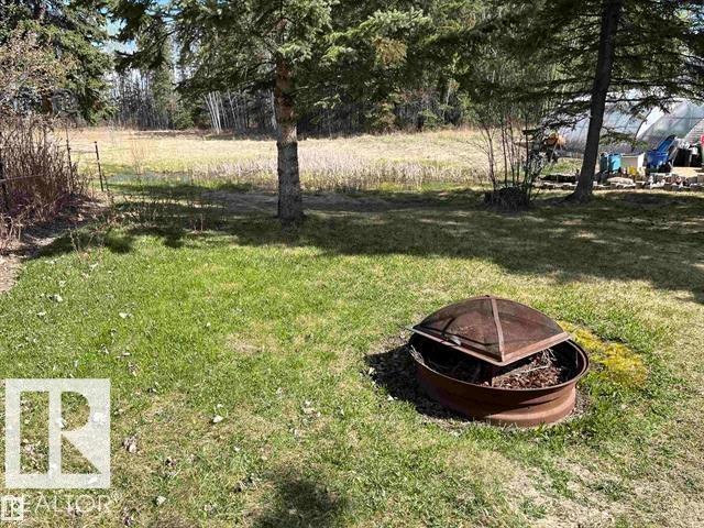 Expansive grass lawn featuring a built-in metal fire pit with a mesh cover - 210 55504 Nikoodi Road, Rural Lac Ste. Anne County, AB - Outdoor