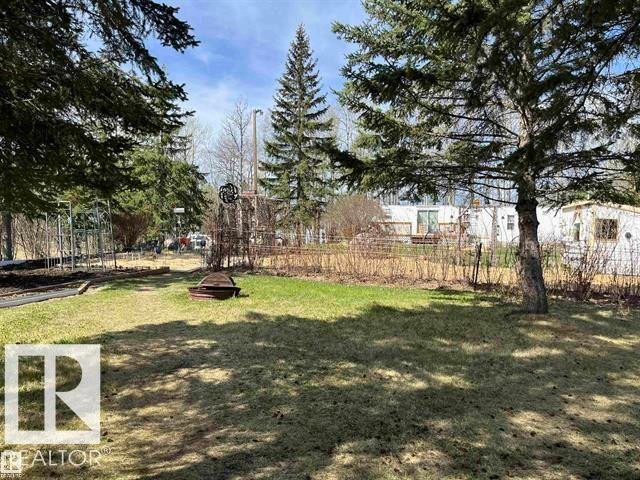 Expansive exterior featuring mature evergreen trees, a fire pit area, and a grassy lawn - 210 55504 Nikoodi Road, Rural Lac Ste. Anne County, AB - Outdoor