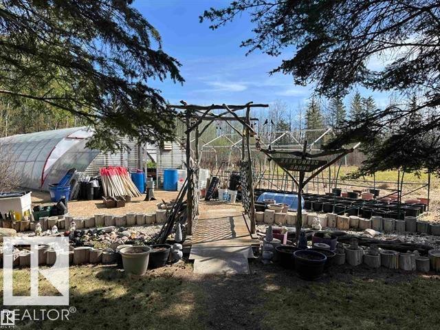 Expansive outdoor area featuring a large greenhouse structure and an adjacent shed - 210 55504 Nikoodi Road, Rural Lac Ste. Anne County, AB - Outdoor