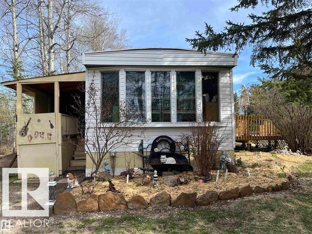 White siding exterior with multiple large windows, a covered entrance, and a wood deck - 210 55504 Nikoodi Road, Rural Lac Ste. Anne County, AB - Outdoor