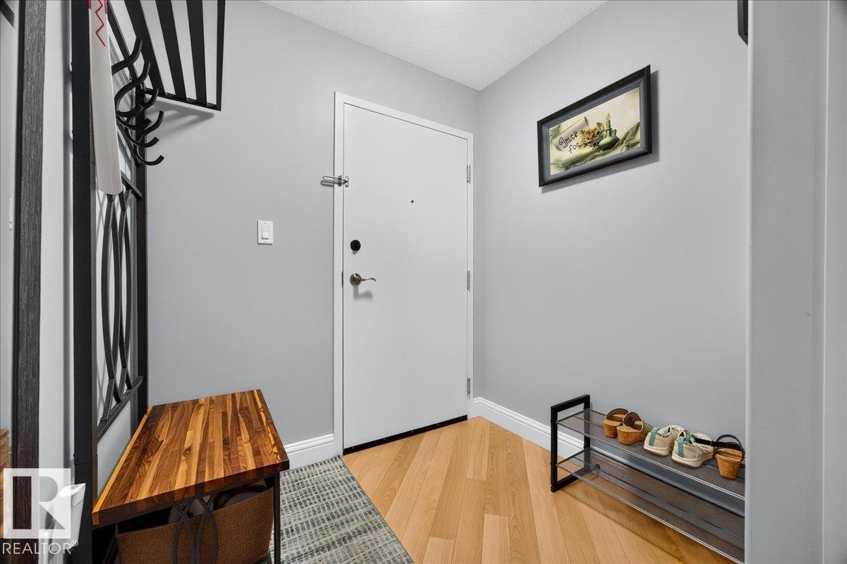 Entryway featuring light wood-finish flooring, light grey painted walls, white baseboards, and a white entry door - #306 13111 140 Av Nw, Edmonton, AB - Indoor Photo Showing Other Room