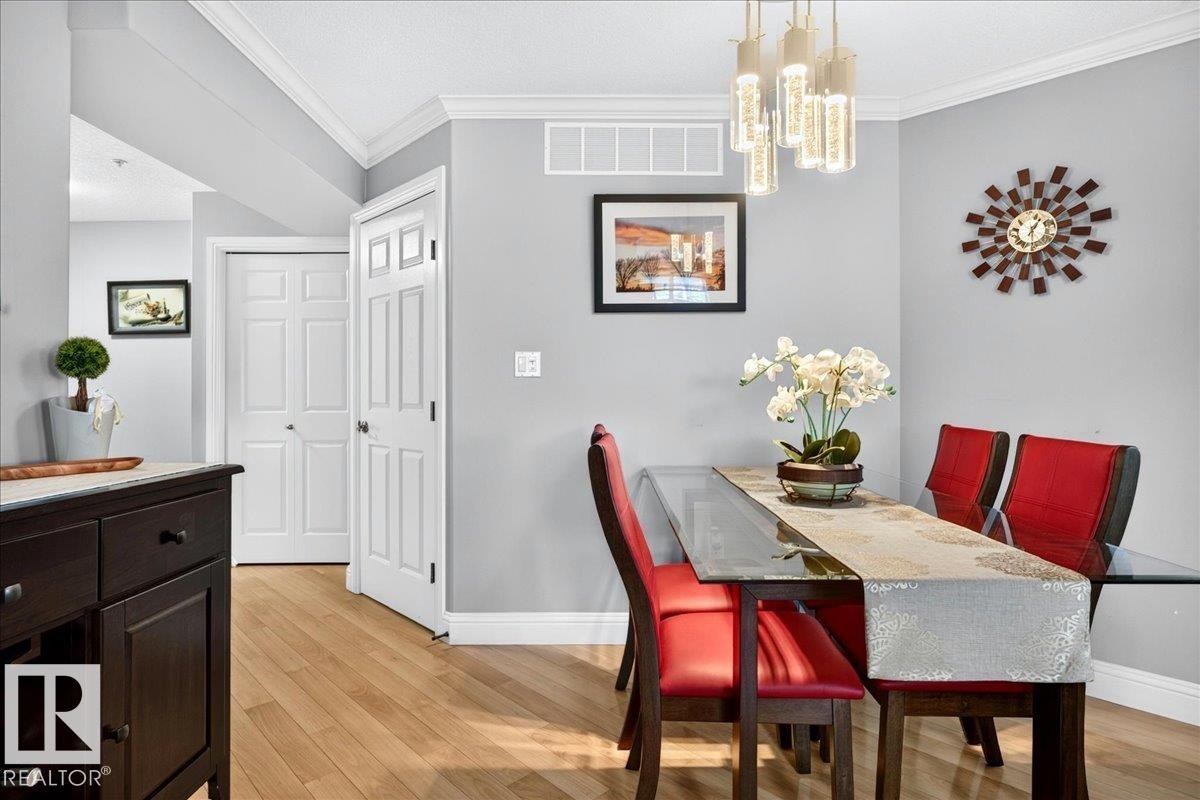 Dining area featuring light wood-finish flooring, crown molding, and a contemporary chandelier - #306 13111 140 Av Nw, Edmonton, AB - Indoor Photo Showing Dining Room