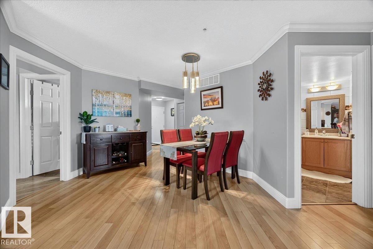 Hardwood-style flooring extends throughout this interior space - #306 13111 140 Av Nw, Edmonton, AB - Indoor Photo Showing Dining Room